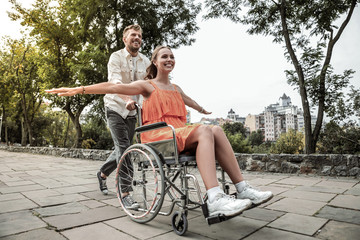 Obraz premium Joyful bearded man driving his partner on wheelchair