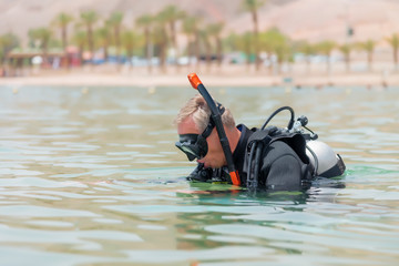 Underwater diver in basic equipment dives into the sea. Lessons of underwater diving. Popular water sport and leisure activity
