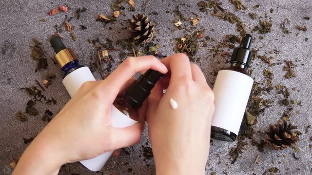 Cosmetics for skin care. A woman puts a drop of cream in the form of a sample and distributes it over the skin of the hands. Beauty concept, cosmetology. Flat lay.