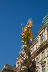 Fototapeta na wymiar Gold finish architectural sculpture atop a building holding cross in Vienna Austria