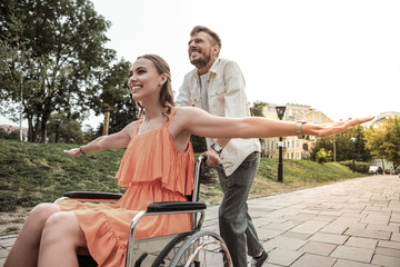 Cheerful bearded man driving his friend on wheelchair