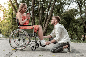 Positive delighted bearded man helping his girlfriend