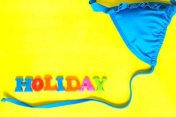 Word Holiday and swim suit on the yellow background.