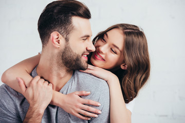 selective focus of happy couple embracing and smiling in bedroom