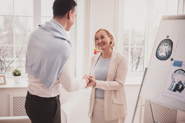 Fototapeta premium Positive delighted female person shaking hands with visitor