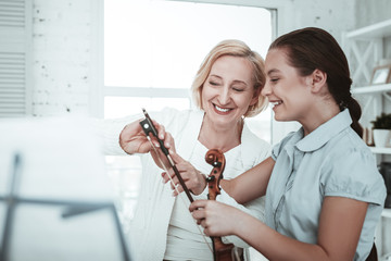 Joyful nice student and teacher looking at the violin bow © Viacheslav Yakobchuk