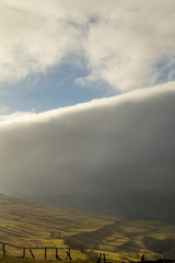 Blanket of clouds converving in cloudscape and landscape of yellow and blue in Yorkshire Dales national Park England United Kingdom