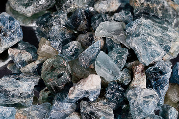 Close up of a variety of uncut blueish and green gem stones filling the frame most with rough surfaces