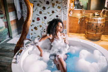 Young woman relaxing in the hydro massage bath covered in foam