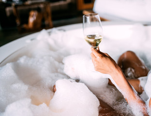 Young woman relaxing in the hydro massage bath covered in foam