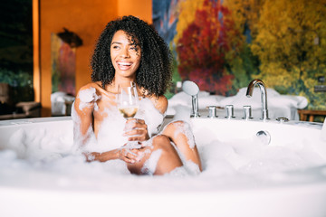 Young woman relaxing in the jacuzzi covered in foam