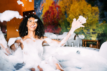 Woman relaxed in the jacuzzi covered in foam - obrazy, fototapety, plakaty