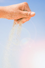 hands are pouring sand by the sea