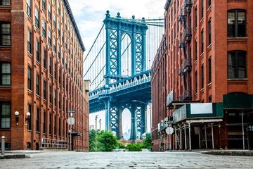 Fotobehang Bruin Manhattan Bridge tussen Manhattan en Brooklyn over East River gezien vanuit een smal steegje omsloten door twee bakstenen gebouwen op een zonnige dag in Washington Street in Dumbo, Brooklyn, NYC