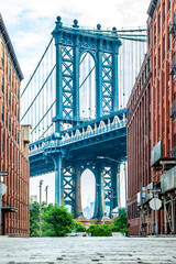 Manhattan Bridge between Manhattan and Brooklyn over East River seen from a narrow alley enclosed...