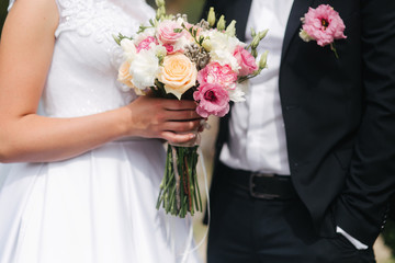 Wedding bouquet in brides hands. Close up view of couples hands holding wedding bouquet. Flowers