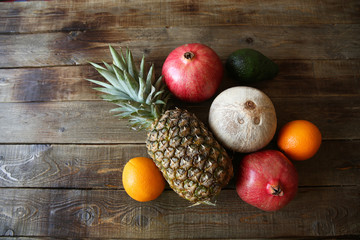 tropical fresh fruits: pineapple, oranges, pomegranate, avocado and coconut on a wooden rustic table with space for text top view, flat lay. Diet. Vegetarian. Food background. Flat lay. Top view.