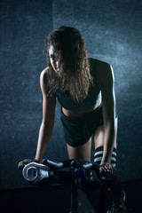 Obraz na płótnie Canvas Young pretty woman riding a bike in the gym
