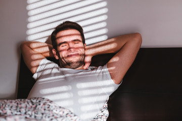 Young man waking up in the bed in the morning