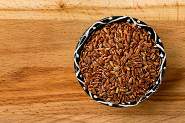 Top view bowl of red rice at wooden board background arranged at right side.