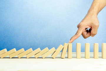 Businessman hand stopping falling wooden blocks, dominoes effect, risk and strategy concept. copy...