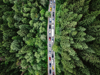 Traffic jam on a road in the middle of a forest. Top down view of cars stuck in traffic. Aerial view shot with a drone (composite photo) - 243909891