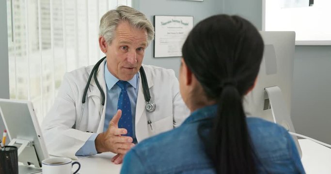 Medical doctor talking to woman patient at desk in slow motion