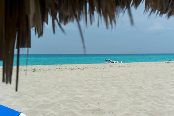 Fototapeta na wymiar Sandy beach with deck chairs under an umbrella. Blue sky ocean