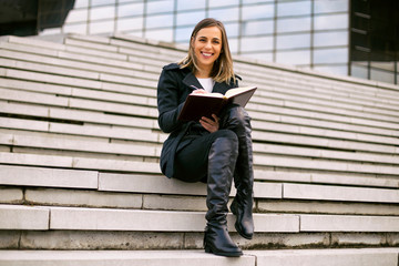 Beautiful businesswoman sitting on the staircase in the city and working.