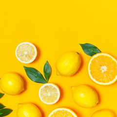 Ripe juicy lemons, orange and green leaves on bright yellow background. Lemon fruit, citrus minimal concept, vitamin C. Creative summer minimalistic background. Flat lay, top view, copy space. - obrazy, fototapety, plakaty