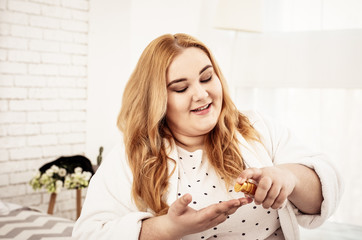 Contented long-haired body positive woman squeezing hair oil
