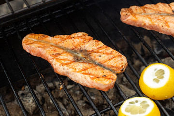 Grilled salmon steak on the flaming and lemon.