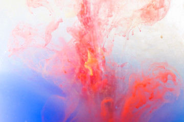 blurred red, purple and blue ink color dropping in water abstract background