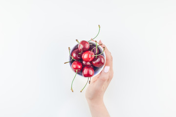 Fresh ripe cherry in a bowl with woman hands