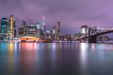 Fototapeta premium View on Financial district with Brooklyn bridge from east river at night with long exposure