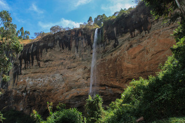 Tall and thin Sipi Falls flowing among rocks in Uganda