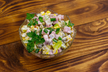 Obraz na płótnie Canvas Tasty salad with sausage, green pea, canned corn, bell pepper, cucumber and mayonnaise on wooden table