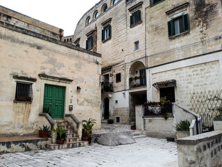 Fototapeta na wymiar Ancient buildings with green shutters and doors to the city of Matera