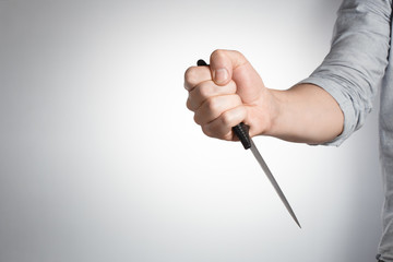 Hand holding big knife on gray background
