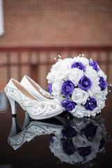 Bouquete of fllowers and beautiful shoes on bricks background. Wedding bouquete and shoes with high heels. Bride`s accessories. Wedding and celebration concept