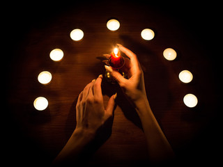 Candles and female hands with sharp nails. Divination and witchcraft, low key.