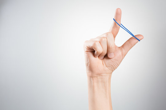 Hand Playing With Elastic Hair Band On Gray Background