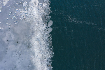 Fototapeta premium Glacier Lagoon with icebergs from above. Aerial View. Cracked Ice from drone view. Background texture concept.
