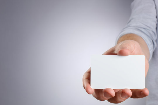 Hand showing white card on gray background