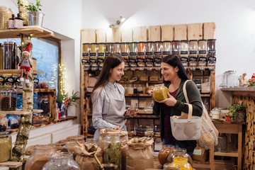 Young woman buying fresh spices and herbs at package free grocery store.