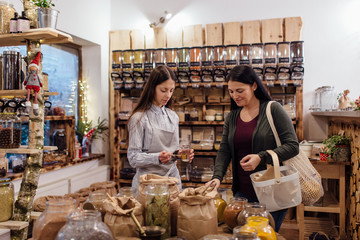 Shopkeeper helping customer in zero waste shop.