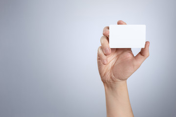Hand showing white card on gray background