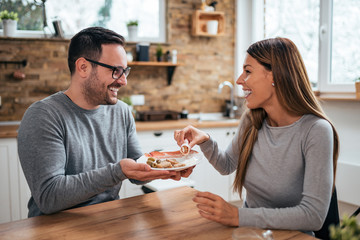 Sweet young couple at the kitchen table with food.