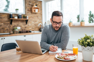 Young stressed man sitting in kitchen in morning at home.