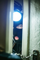 burglar with torch opens door of appartment